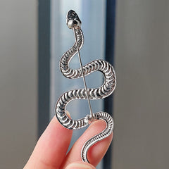 Gold snake brooch on white fabric